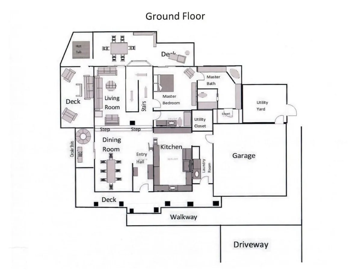 An open-concept view from inside the home, showing the living room, kitchen, dining room, and deck with a glimpse of the hot tub. The space is designed for easy movement and features ample seating for family gatherings or group meals. Large windows and patio doors visually and physically connect the interior with the outdoor deck, reinforcing accessibility and togetherness.