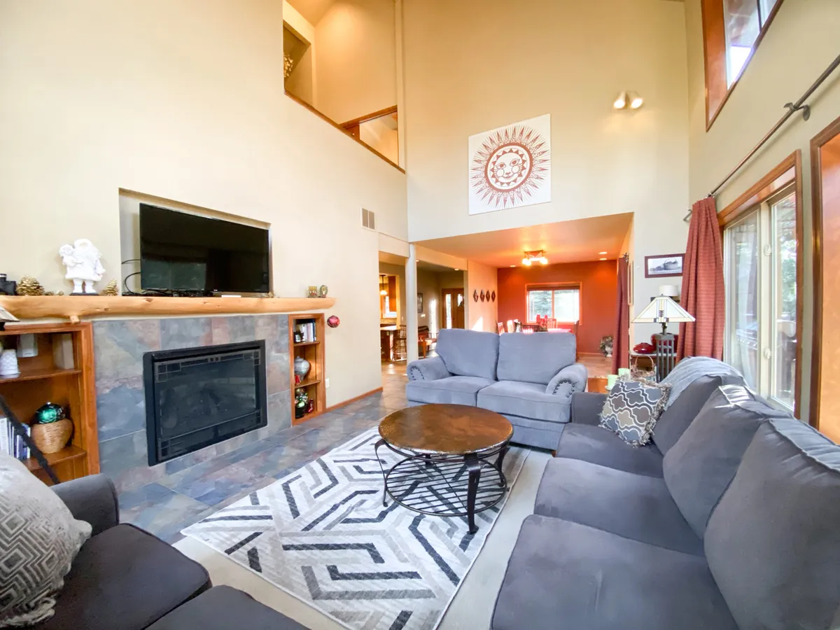 The image showcases a cozy, welcoming living room with a plush sofa set arranged around a crackling fireplace. Stylish wall art adds a modern touch, while the spacious layout invites guests to relax, socialize, or gather for movie nights.