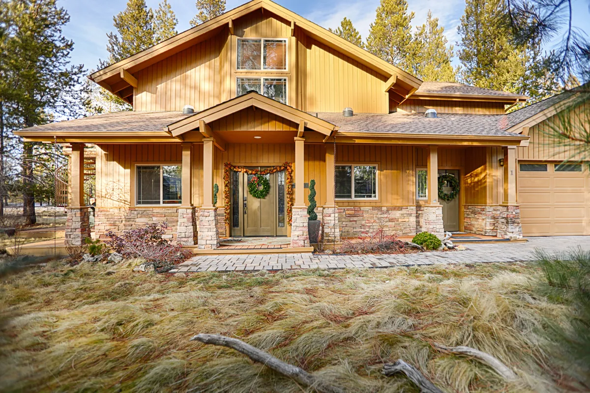 A welcoming front porch with stonework, charming wreaths on the doors, and plenty of space for family members to gather before heading out or returning from a day of adventure. The inviting entryway hints at the warmth and hospitality inside the home, while its outdoor setting connects with the surrounding nature of Sunriver.